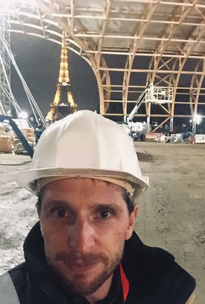 Guillaume Tizon en casque de chantier, de nuit, sous la charpente du Grand Palais Éphémère
